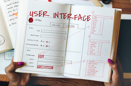 female hands holding a notebook with a wireframe drawing and three component sketches
